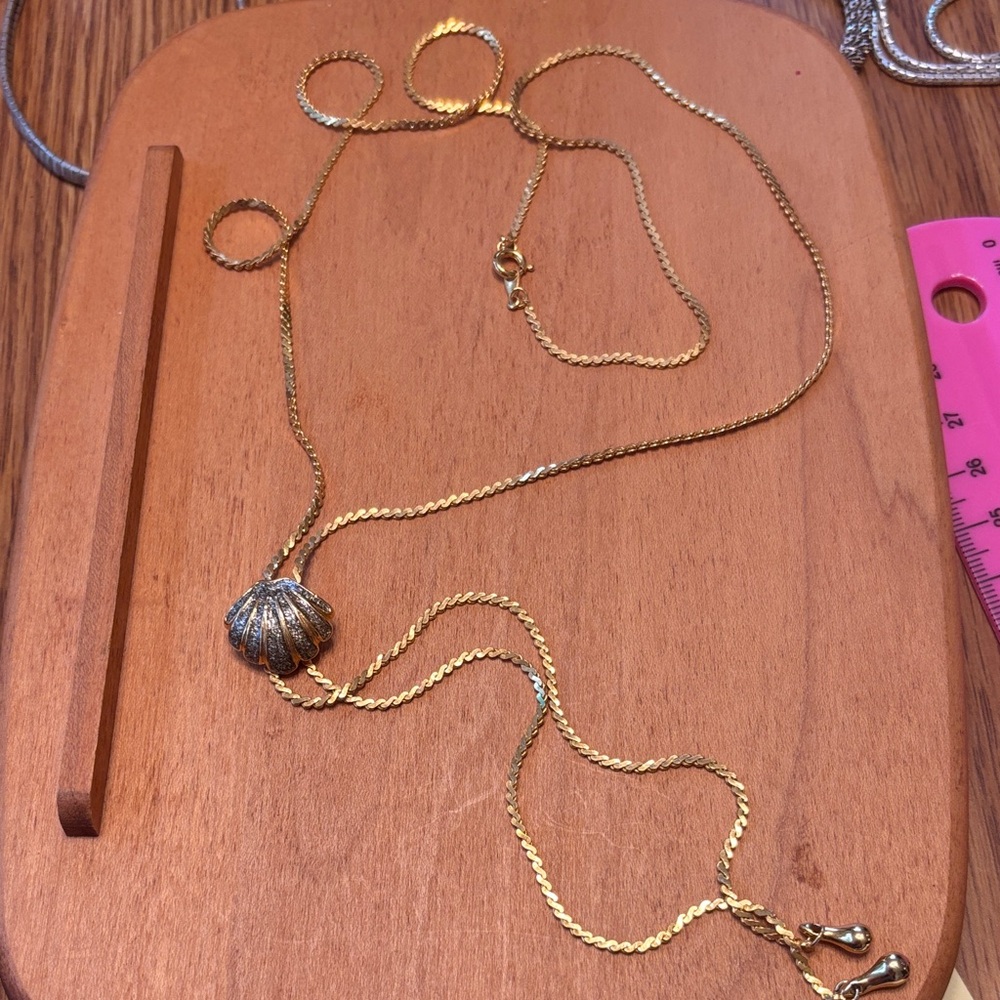 Gold tone twisted chain necklace with a ribbed pave shell charm